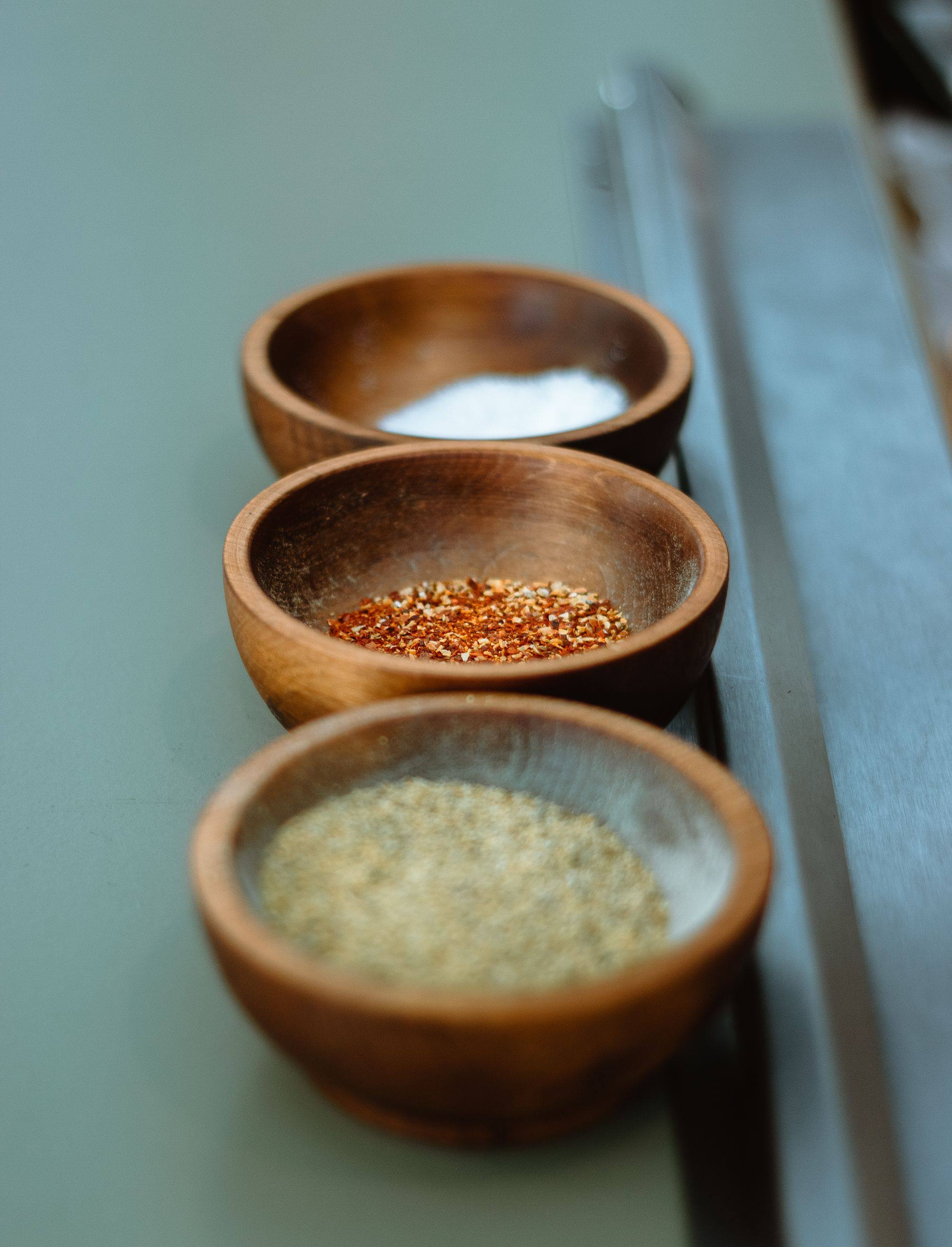 Salt, chilli and a herb blend in three wooden bowls